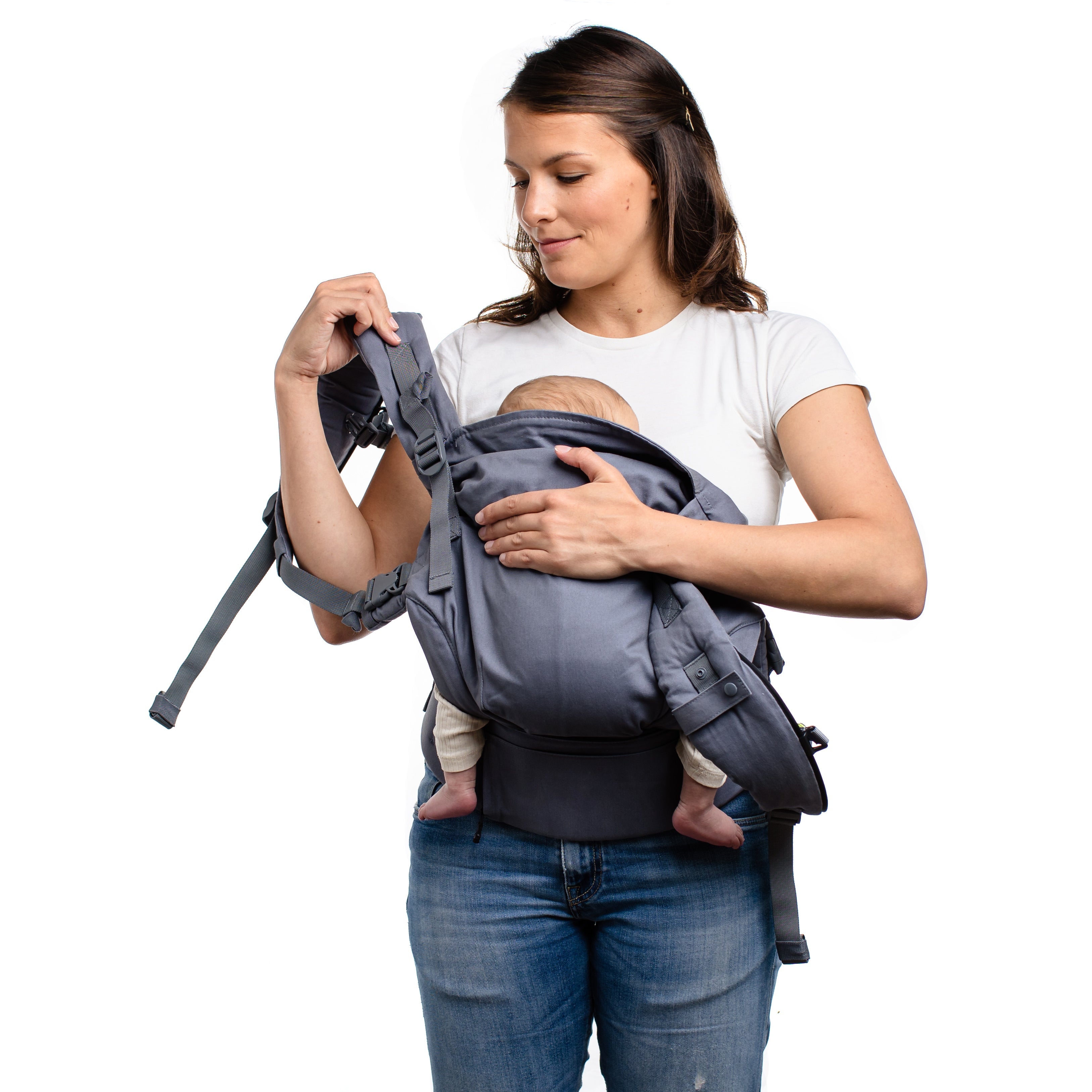 Confident young mom putting her baby in a front carry position in the gray boba x baby carrier.
